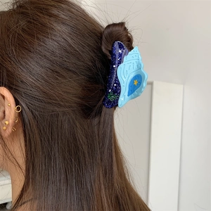 Pince à cheveux coquillage bleu avec étoiles et algues portée sur le côté