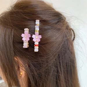 Détail de barrettes fleurs de cerisier avec pétales roses et strass brillants sur cheveux