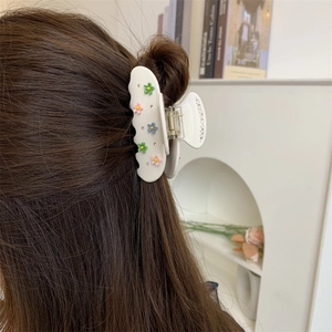 Grande pince à cheveux crème avec fleurs colorées et strass sur de longs cheveux bruns