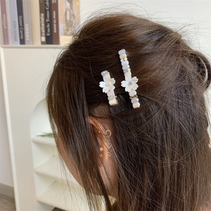 Vue détaillée des barrettes florales avec fleurs en résine blanche et perles colorées