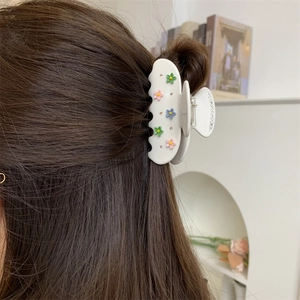 Pince à cheveux blanche en résine avec fleurs et strass dans une coiffure mi-haute