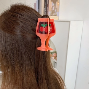 Detail of orange acetate hair claw in juice glass shape with cherry pattern on hair