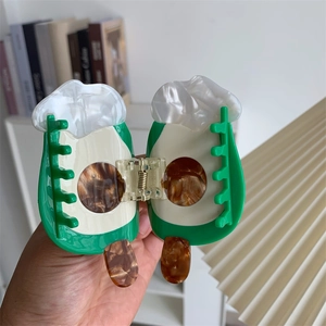 Detail view of a green and white popsicle shaped acetate hair claw clip with tortoise texture