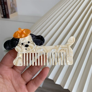 Dettaglio di pettine per capelli in acetato a forma di cane con texture marmorea e berretto arancione