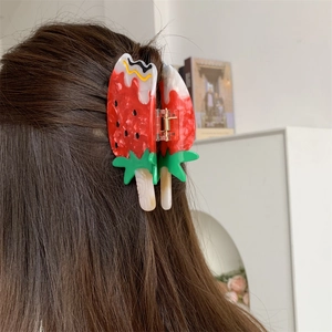 Detail of creative strawberry popsicle hair claw clip worn on dark brown hair