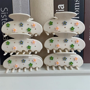 Détail des pinces à cheveux blanc crème avec fleurs 3D colorées et petits strass fins