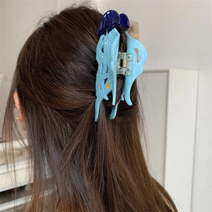 Détail d'une pince à cheveux méduse bleue avec motifs d'étoiles sur cheveux sombres