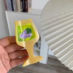 Detail of a goblet-shaped cream acetate hair claw clip featuring grape decorations