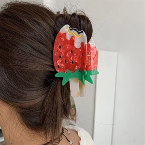 Close-up of strawberry popsicle hair claw clip made of acetic acid on brown hair bun