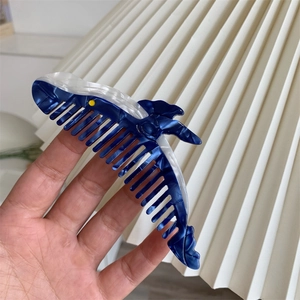 Dettaglio di un fermaglio per capelli a forma di squalo in acetato marmorizzato blu e bianco