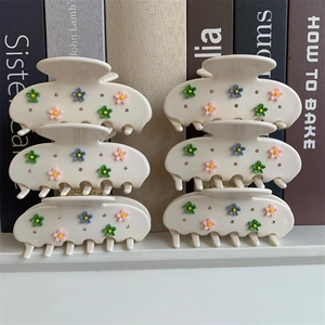 Détail de grandes pinces à cheveux crème avec fleurs 3D et strass brillants