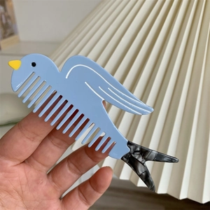 Dettaglio del pettine creativo a forma di uccello in acetato azzurro con texture marmorizzata