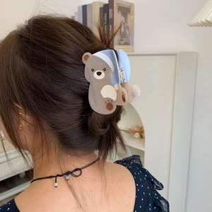 Detailopname van een bruine beren haarklem met blauwe hoed tegen een warme achtergrond