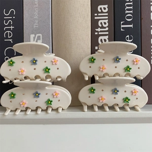 Vue détaillée des pinces à cheveux crème avec motifs floraux colorés et strass brillants décoratifs