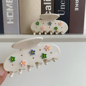 Détail de la pince à cheveux en acétate crème avec fleurs et strass étincelants
