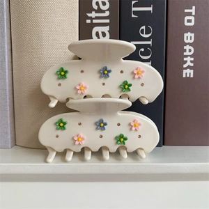 Détail de pinces à cheveux en acétate crème avec fleurs 3D colorées et strass brillants