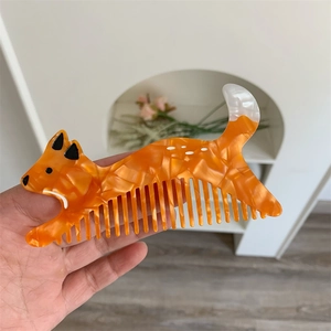 Dettaglio di un piccolo pettine per capelli in acetato a forma di volpe con trama marmorizzata