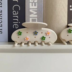 Vue détaillée d'une pince à cheveux crème avec fleurs 3D colorées et strass brillants