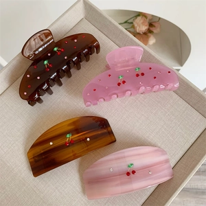Detailed set of four acrylic hair claws and clips featuring red rhinestone cherry motifs