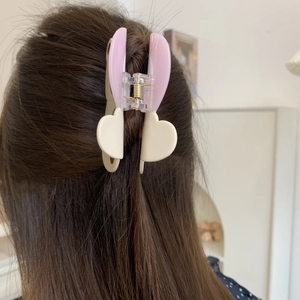 Detailoverzicht van roze en beige acetaat haarklem gedragen op het haar van model