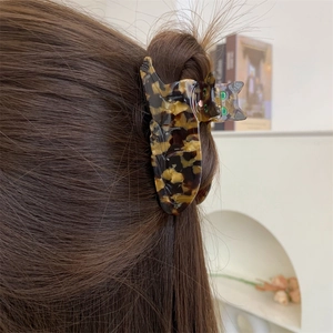 Detailed close-up of a tortoiseshell acetate cat hair claw clip worn on straight brown hair