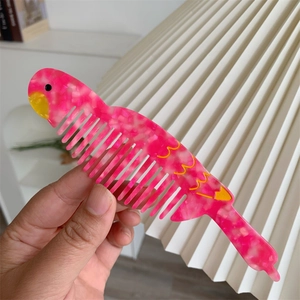 Dettaglio del pettine creativo a forma di pappagallo in acetato con trama rosa marmo