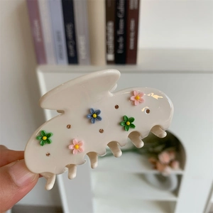 Gros plan détaillé d'une pince à cheveux en acétate crème avec fleurs colorées et strass