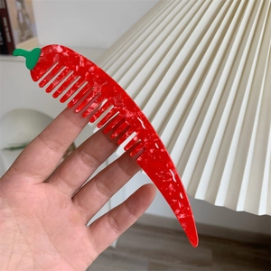 Dettaglio del pettine in acetato a forma di peperoncino con trama marmorizzata e gambo