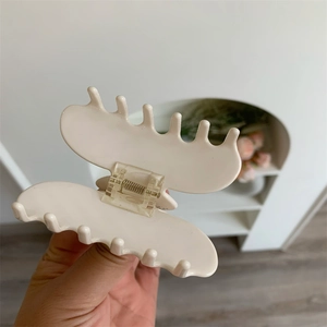 Détail d'une grande pince à cheveux en acétate crème avec ressort métallique et dents