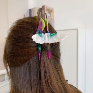 Close-up of a colorful hummingbird hair claw clip made of acetate worn on long hair