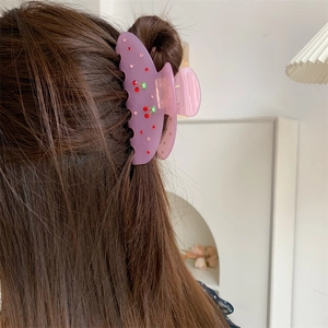 Elegant purple hair claw clip with cherry pattern and rhinestones worn by a model