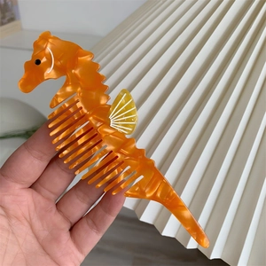 Dettaglio del pettine a forma di cavalluccio marino in acetato arancione effetto marmo
