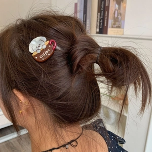 Close-up of cute white puppy and coffee cup acetate hair clip worn on model's hair
