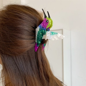Detailed back view of a woman wearing a marble-textured acetate hummingbird hair claw clip
