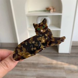 Detail of creative acetate cat hair claw clip featuring tortoiseshell pattern and green eyes