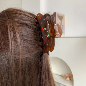 Close-up of a large brown translucent hair claw with sparkling red rhinestone cherries