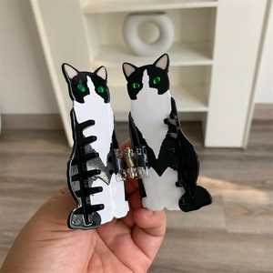 Detail view of tuxedo cat acetate hair claw clip with green eyes and metal spring