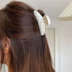 Détail d'une pince à cheveux à fleurs avec strass portée sur la chevelure