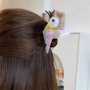 Detailed back view of a colorful hummingbird hair claw clip worn in a half-up hairstyle