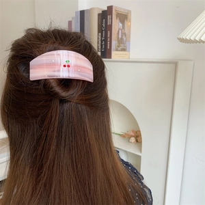 Detail of pink striped acetate hair clip with red cherry pattern and sparkling rhinestones