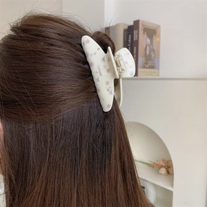 Détail de la pince à cheveux crème à motifs floraux et strass sur cheveux bruns