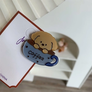 Close-up of a cartoon puppy in a coffee cup acetate hair clip on a white display card