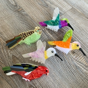 Macro detail of bird-shaped acetate hair claws with colorful marble texture and pearly finish