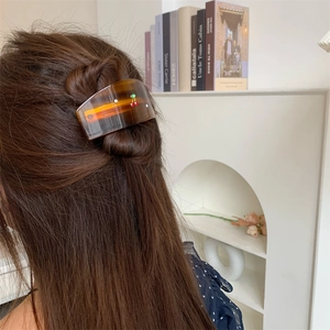 Detail of tortoise shell hair claw with red cherry design and rhinestones on long hair