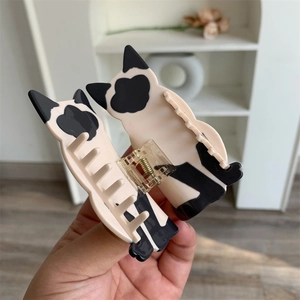 Detail of creative cat shaped acetate hair claw clip with black spots and gold spring