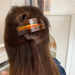 Detail view of amber tortoise hair claw clip with cherry rhinestone accent on hair