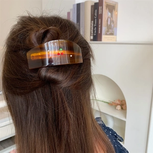 Detail of amber tortoiseshell hair claw clip with crystal cherry motif on model's hair