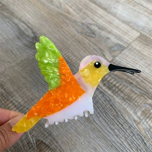 Detailed close-up of a colorful hummingbird claw clip with marble texture for hair