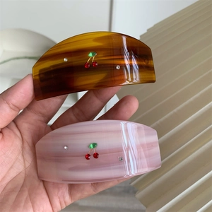 Close-up of cherry crystal hair claws in amber and marble white with resin finish