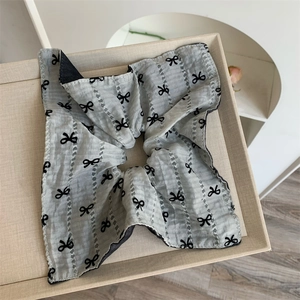 Macro shot of grey cotton-linen scrunchie with black bow prints and eyelet embroidery